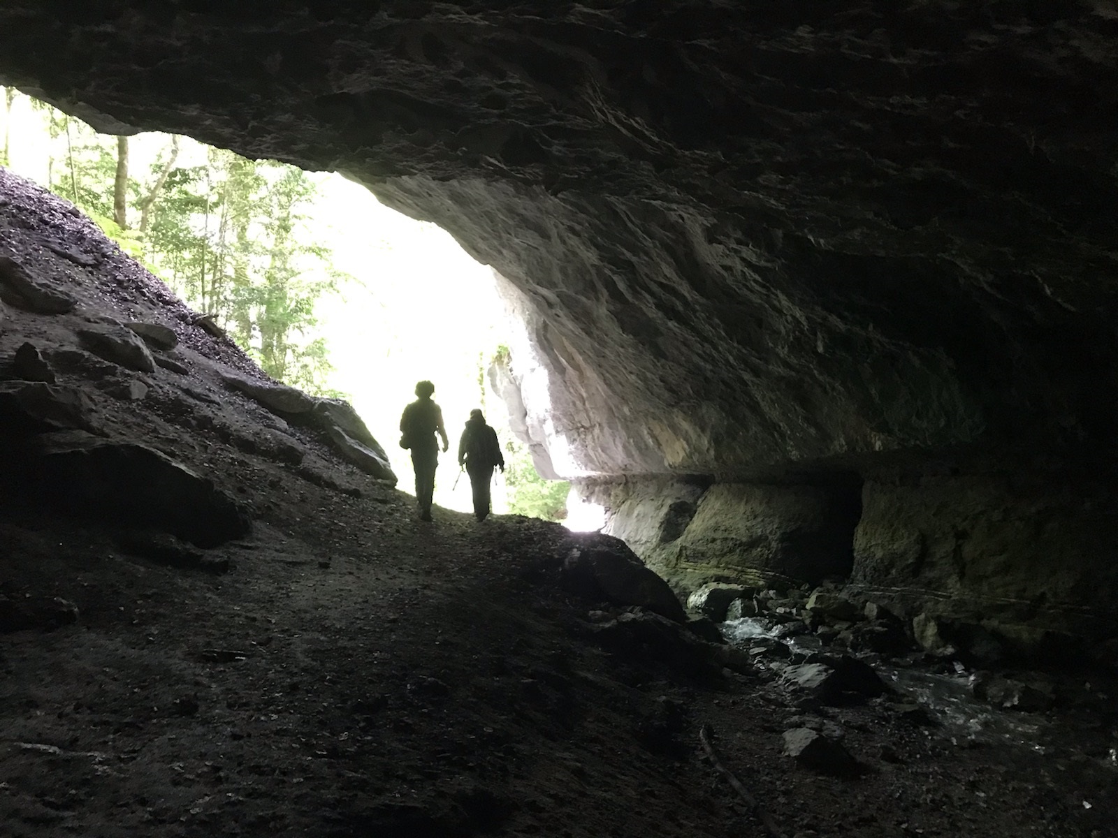 Photo de Faustin et Charline en train de sortir de la grotte, au milieu de son entrée qui est en forme d'amande allongée